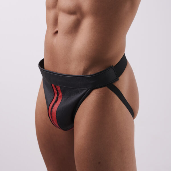 Jockstrap ma szeroki pas w talii, który zapinany jest na rzepy po bokach, oraz elastyczne paski biegnące pod pośladkami. Przód wykonany jest z czarnej ekoskóry z czerwonym paskiem widocznym zamkiem na środku.